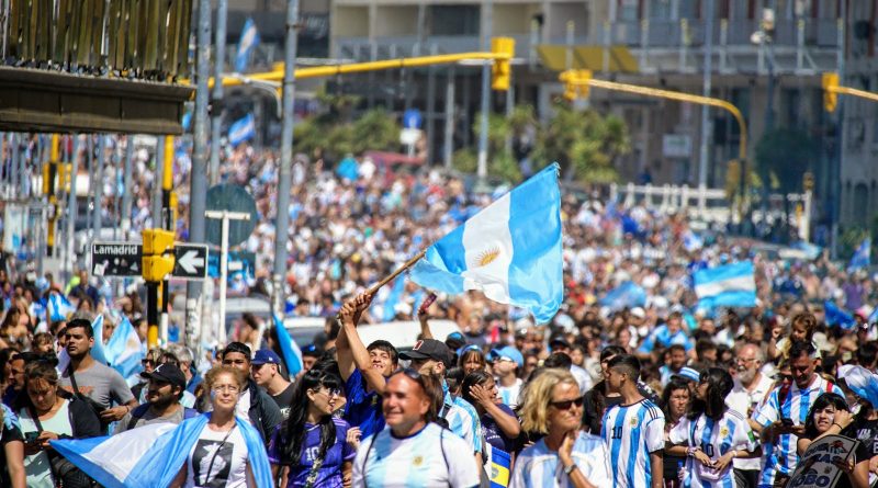 A crowd of people walking down a street with argentina flags